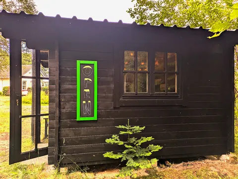 A small black building with a green sign that says "open" on it.