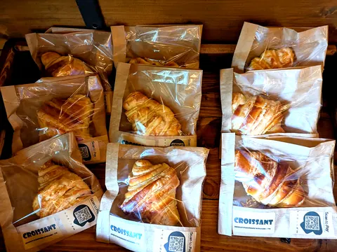A table with a bunch of croissants in plastic bags.