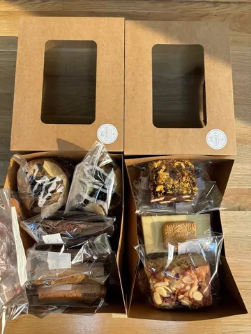 A box of food with two compartments, one containing cookies and the other containing cakes.