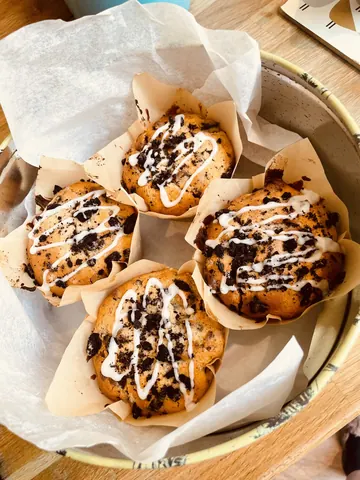 A plate of cupcakes with white frosting and chocolate chips.