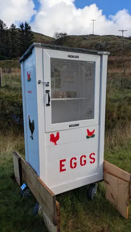 A small white building with a chicken on it.