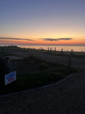 A sign that says "Cake Sidd" is sitting on a fence.