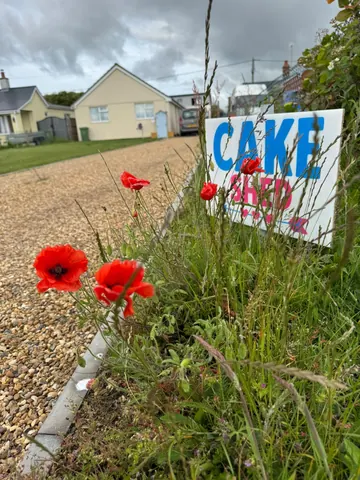 A sign that says "cake shop" is on the side of the road.