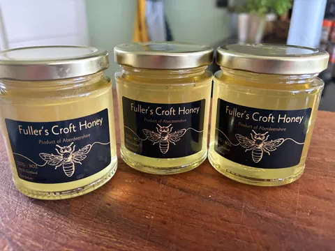 Three jars of honey are on a table.