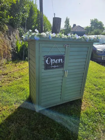 A green shed with a sign that says open.