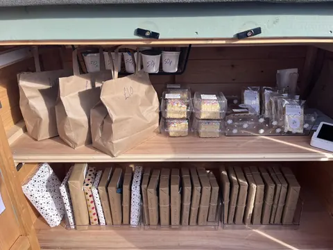 A wooden shelf with bags of food on it.