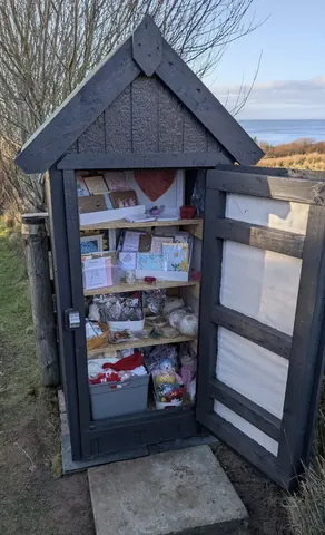 A small wooden structure with a shelf inside.