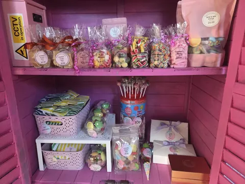 A pink shelf with a variety of candy and candies on it.