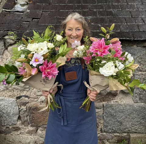 A woman is holding two bouquets of flowers.