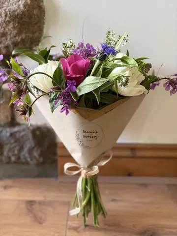 A bouquet of flowers in a brown paper bag.