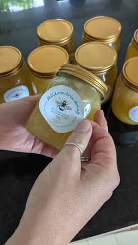 A jar of honey is being held by a person.