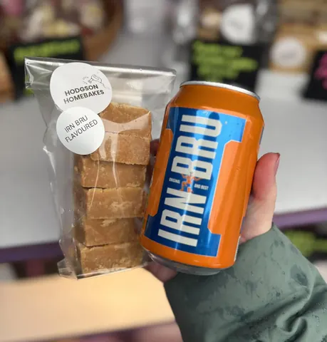 A person holding a can of Irn Bru and a bar of honeycomb.