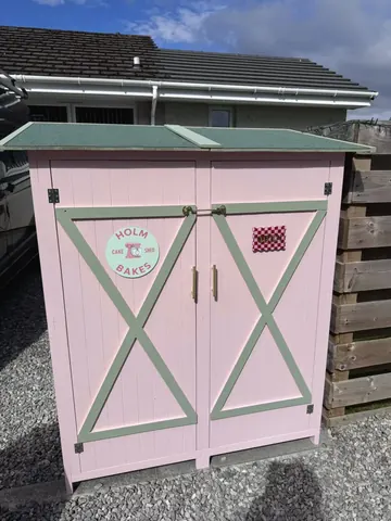 A pink building with a green door and a checkered pattern on it.