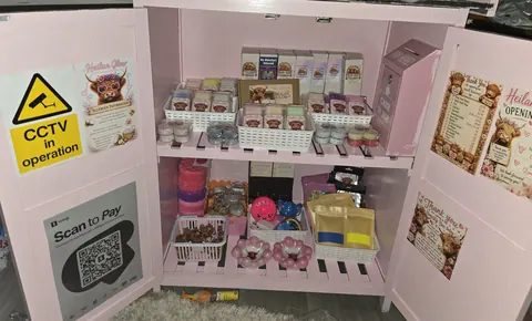 A pink cabinet with a shelf full of toys and candles.