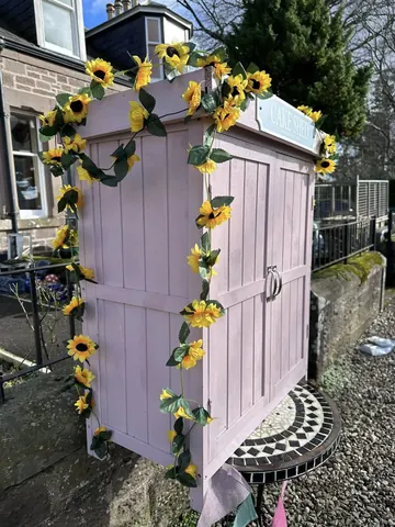 A pink cabinet with yellow flowers on it.