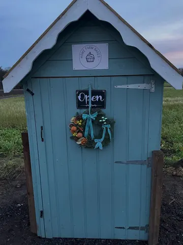 A blue shed with a sign that says "open" on it.