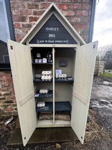 A small wooden shed with a sign that says Honesty Shed.