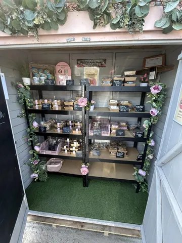 A small room with a shelf full of food and flowers.