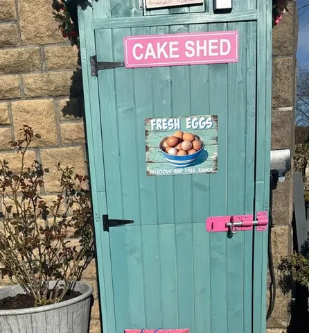 A blue door with a pink sign that says "Cake Shed" on it.