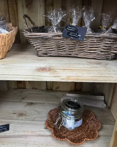 A jar of jam is sitting on a wooden shelf.
