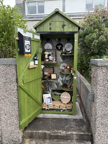 A green shed with a sign on the door.