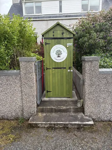 A green shed with a tree on it.