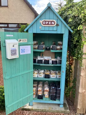 A blue shed with a sign that says open.