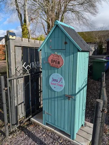 A blue shed with a sign that says "open" on it.