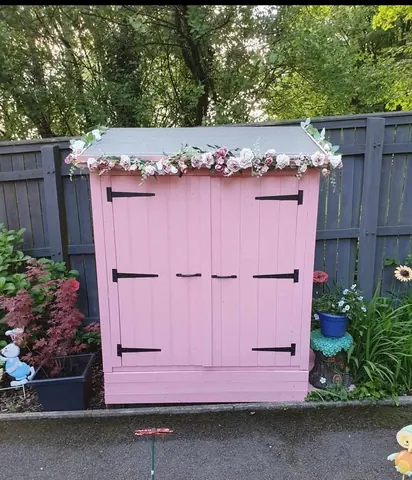 A pink shed with flowers on it.
