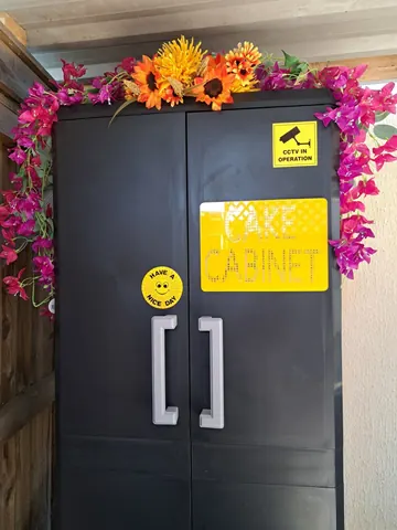 A black refrigerator with a yellow sign on it.