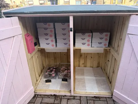 A pink box with a white lid and a white box with a pink lid.