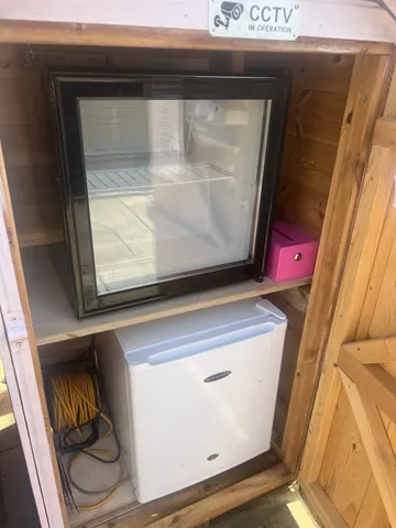 A white refrigerator and a black refrigerator are sitting next to each other.