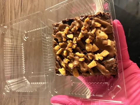 A hand holding a piece of chocolate cake.