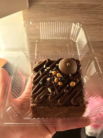 A person is holding a piece of cake in a plastic container.