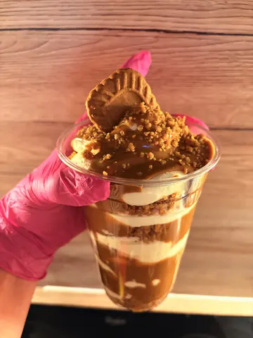 A person is holding a cup with a cookie in it.