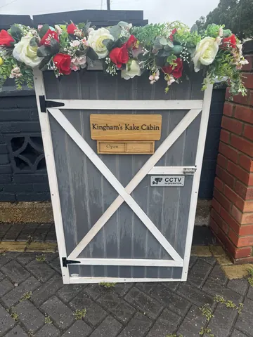 A small wooden structure with a sign on it that says "Kingham's Kake Cabin".