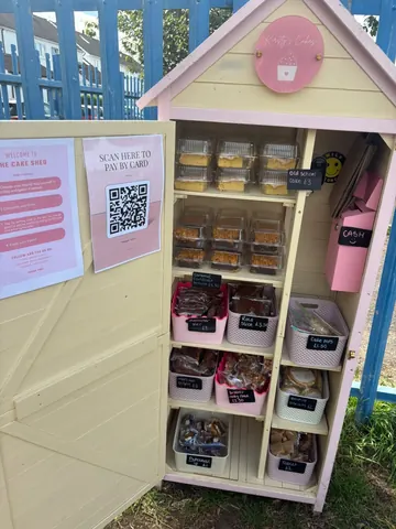 A small wooden structure with a pink door and a sign that says "scan here to pay by card".