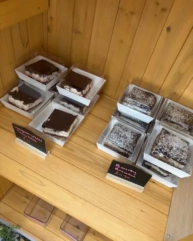 A wooden table with several boxes of desserts on it.