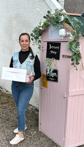 A woman is standing in front of a pink building.
