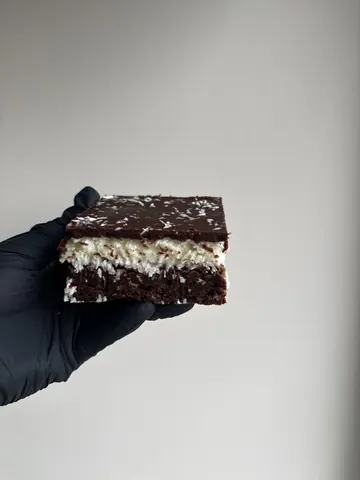 A hand holding a piece of chocolate cake.