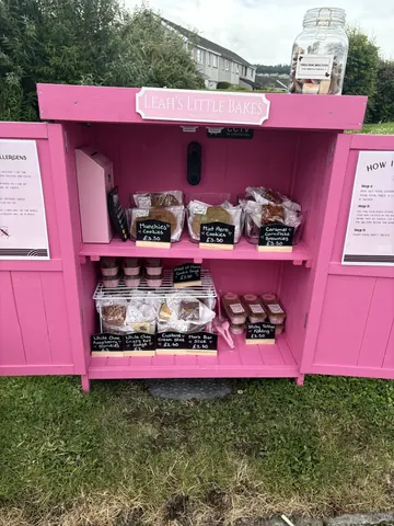 A pink food stand with a sign that says "Leah's Little Bakes" on it.
