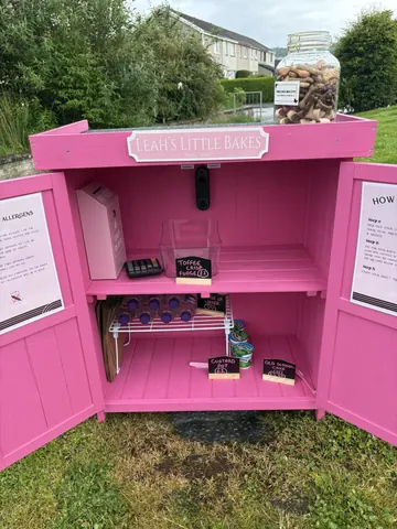 A pink box with a sign that says "Leah's Little Bakes" on it.