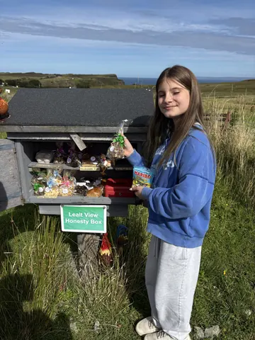 A woman is standing next to a grill with food in it.