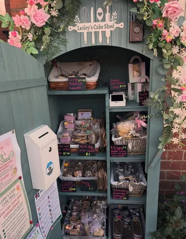 A small green building with a sign that says "Lessley's Cake Shop" on it.