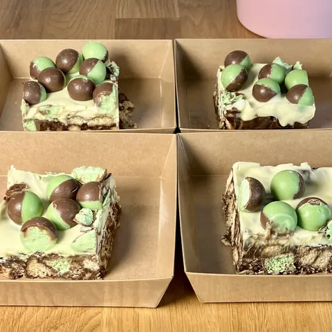 Four square boxes of desserts with chocolate and green candies.
