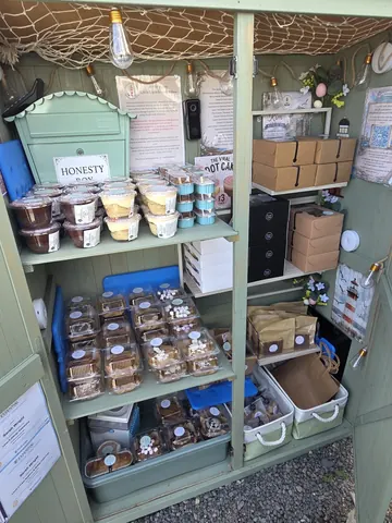 A small green building with a shelf full of food.