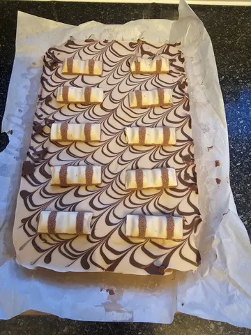 A cake with white and brown frosting.