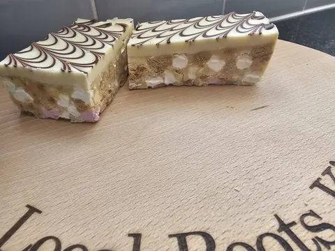 A wooden cutting board with two pieces of cake on it.