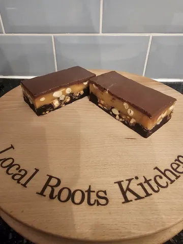 A wooden cutting board with two pieces of chocolate cake on it.