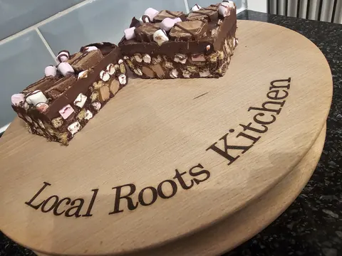 A wooden board with the words "Local Roots Kitchen" written on it.